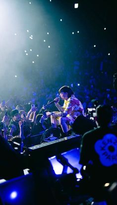 a man sitting on top of a table in front of a crowd at a concert