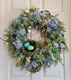 a wreath with blue flowers and eggs on it