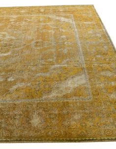 an antique rug with yellow and blue colors on the ground, in front of a white background