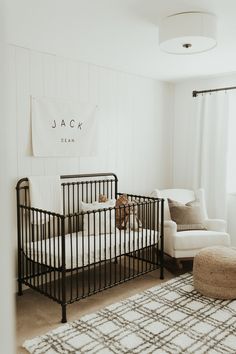 a baby's room with white walls and black metal crib