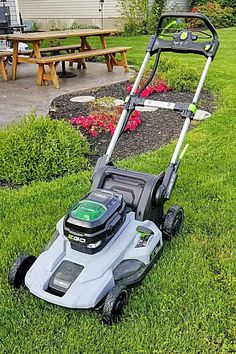 a lawn mower sitting in the grass next to a picnic table