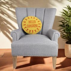 a blue chair with a yellow pillow that says hello sunshine on it and a potted plant in the background