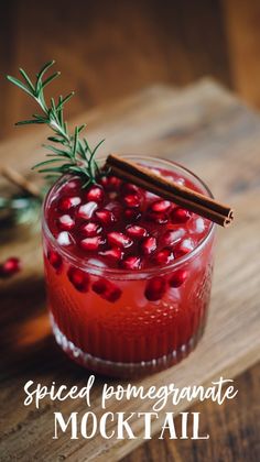 a drink with pomegranate and cinnamon on the rim, garnished with an rosemary sprig