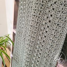 a crocheted blanket sitting next to a potted plant