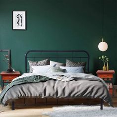 a bedroom with dark green walls and white rugs on the wooden floor, along with a metal bed frame