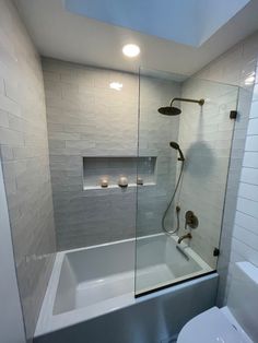 a white toilet sitting next to a bath tub under a skylight in a bathroom