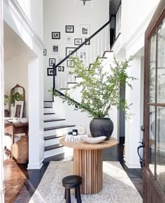 an entryway with stairs and a table in the center, surrounded by pictures on the wall