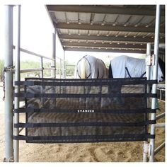 two horses are standing under a metal structure