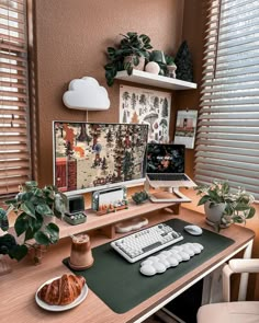 a desk with a computer, keyboard and plant on it