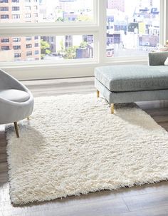 a living room with a couch, chair and rug in front of a large window