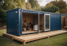 a large blue shipping container sitting on top of a wooden deck next to a picnic table