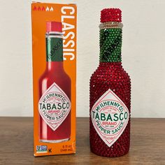 a bottle with red and green beads next to an orange box on a wooden table