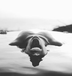 a black and white photo of an animal with its mouth wide open in the water