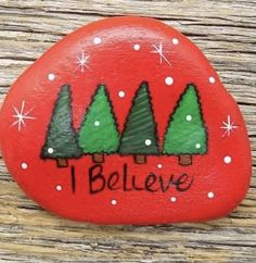 a painted rock with trees on it that says i believe