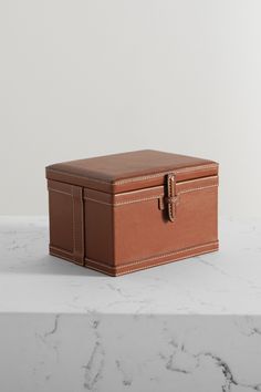 a brown leather box sitting on top of a white marble countertop next to a wall