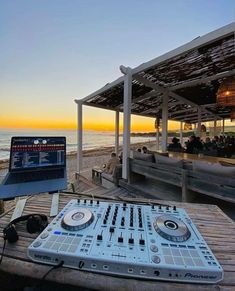 a laptop computer sitting on top of a wooden table next to a dj's deck