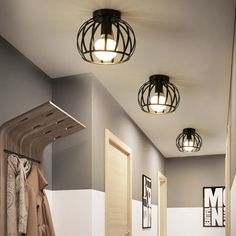 three lights are hanging from the ceiling in a hallway with coat racks and clothes on hangers