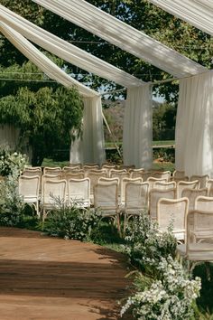 an outdoor ceremony with white drapes and chairs set up for a wedding or special event