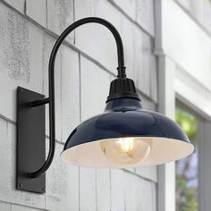 an outdoor wall light on the side of a building with a brick wall behind it