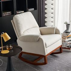 a white recliner chair sitting in a living room next to a table with a lamp on it