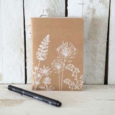 a notepad with a drawing of flowers on it and a pen next to it