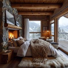 a bedroom with a stone fireplace in the corner and large windows on both sides that look out onto mountains