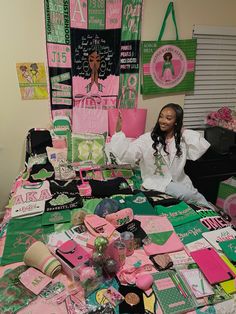 a woman sitting at a table covered in pink and green items