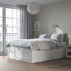 a white bed sitting next to a window in a bedroom