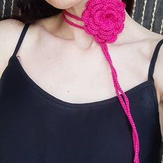 a woman wearing a pink crocheted flower necklace