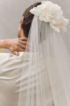 the back of a bride's head wearing a white veil and flower in her hair