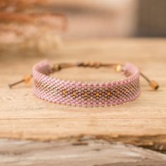 a pink beaded bracelet sitting on top of a wooden table