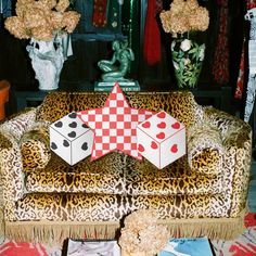 an animal print chair with two dices on it and flowers in vases next to it