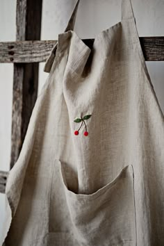 a bag hanging from a wooden chair with cherries embroidered on the front and side