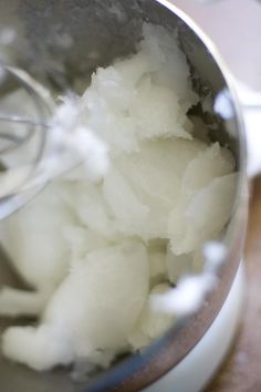 a metal bowl filled with white food on top of a wooden table