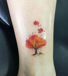 a small tree with leaves on it's foot is painted in red and orange