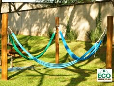 a blue hammock tied to wooden posts in the yard with grass and trees