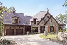 a large stone house with two garages on the front and one story above it