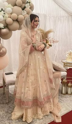 a woman in a wedding dress standing next to a table with balloons and flowers on it