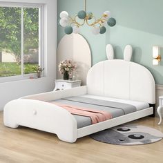 a white bed sitting on top of a hard wood floor next to a wall mounted mirror