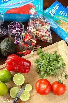 the ingredients for this mexican salad are neatly arranged on a cutting board, along with limes, tomatoes, onions, and peppers