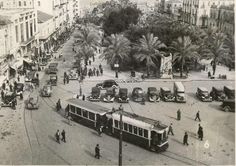 an old black and white photo of a city street filled with cars, buses and people