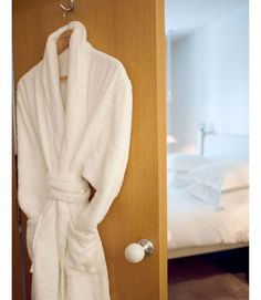 a white robe hanging on the wall next to a bed in a room with a wooden door