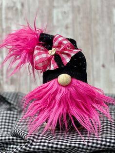 a pink stuffed animal wearing a black and white checkered hat with a bow on it's head