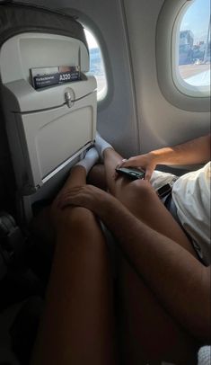 a person sitting on an airplane seat with their legs crossed