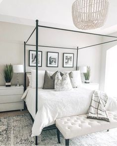 a bedroom with white bedding and pictures on the wall above it's headboard