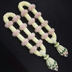 some white and pink flowers on a black surface with one flower hanging from it's end