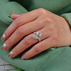 a woman's hand wearing a ring with two diamonds on the middle of it