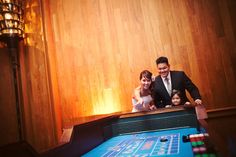 a man and woman standing next to a casino table