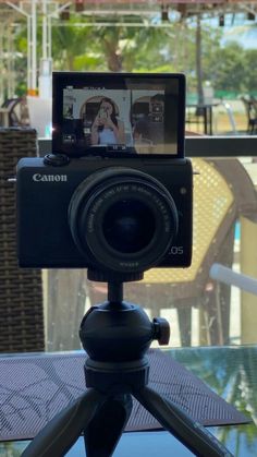 a camera sitting on top of a tripod in front of a table with chairs