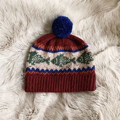 a red and blue knitted hat laying on top of a white furnishing